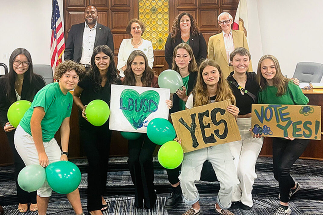 students with signs and balloons with school district members