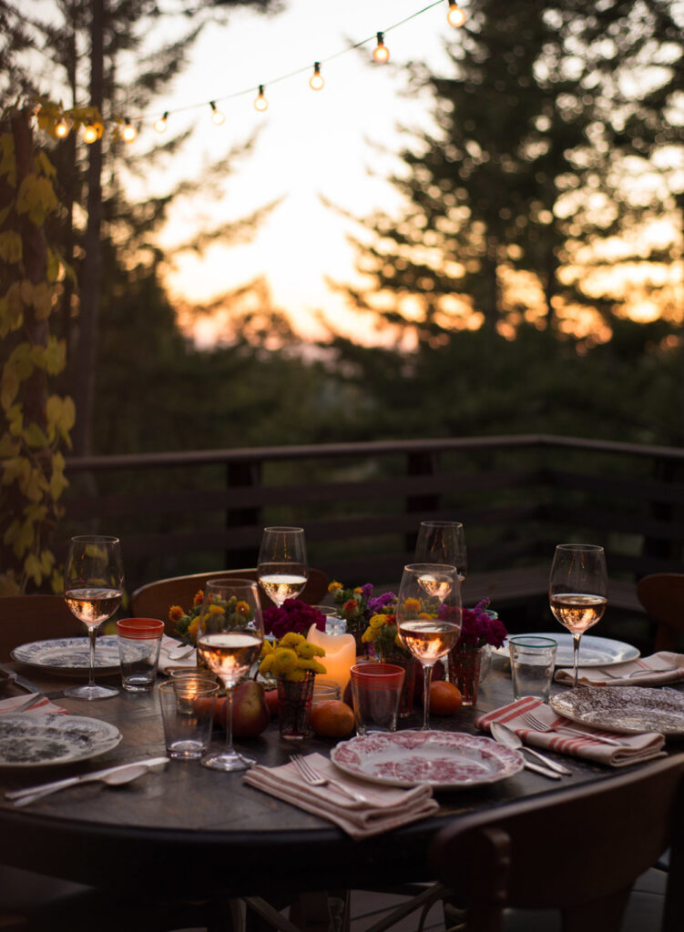 outdoor table setting at sunset with candles and pine trees